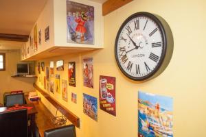 eine Uhr an einer Wand mit Bildern und Plakaten in der Unterkunft Chateau de Camurac in Camurac