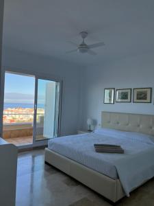 ein weißes Schlafzimmer mit einem Bett und einem großen Fenster in der Unterkunft Luxury House with 3 Bedrooms, Sea Wiew and Swimming Pool in a quiet Residence in Puerto de Santiago + 16 Fotos