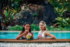 dos chicas sentadas en una mesa junto a una piscina en Roost Glamping - SHA Certified en Rawai Beach