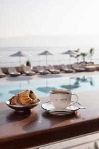filiżankę kawy i ciasto na stole obok basenu w obiekcie Galei Kinneret Hotel w mieście Tyberiada