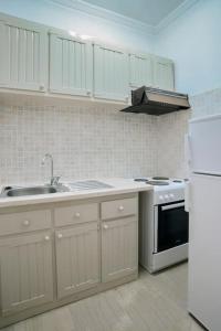 eine Küche mit weißen Schränken, einer Spüle und einem Kühlschrank in der Unterkunft Babis - LOGGOS APARTMENTS in Longós