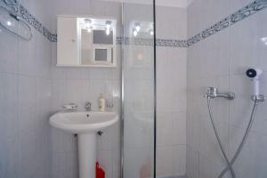 ein weißes Bad mit einem Waschbecken und einer Dusche in der Unterkunft Babis - LOGGOS APARTMENTS in Longós