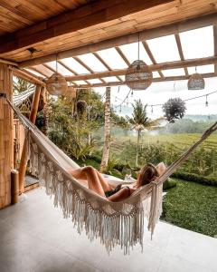 a woman laying in a hammock on a patio at Magic Hills Bali - Magical Eco-Luxury Lodge in Selat