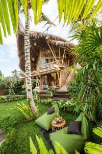 atropical house with green cushions in a garden at Magic Hills Bali - Magical Eco-Luxury Lodge in Selat