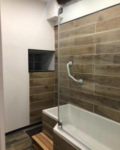 a bathroom with a tub and a tv on the wall at En toute simplicité in Bielle