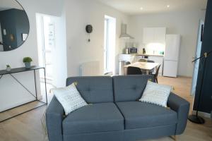 a living room with a blue couch and a kitchen at T2 de 55m2 avec toit terrasse, hyper centre, wifi, draps, savons et serviettes fournis in Cognac