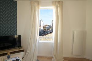 a living room with a window with white curtains at T2 de 55m2 avec toit terrasse, hyper centre, wifi, draps, savons et serviettes fournis in Cognac
