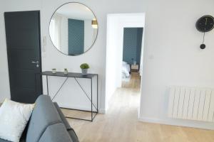 a living room with a gray couch and a mirror at T2 de 55m2 avec toit terrasse, hyper centre, wifi, draps, savons et serviettes fournis in Cognac