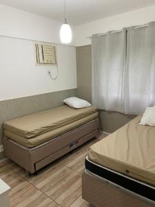 two twin beds in a room with a window at Porto Real Suites Mangaratiba in Mangaratiba