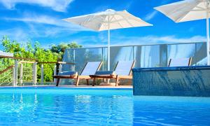 a pool with chairs and umbrellas next to a swimming pool at Perla Villas with Heated Pool in Kávallos