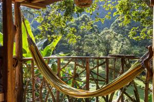 a hammock on a porch with a view of a forest at Las Cabanas, Finca Flora del Rio in Pijao