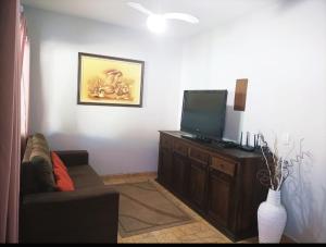 a living room with a couch and a flat screen tv at Lindo Sobrado c/ Piscina e conforto próximo do mar in Itapoa