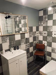 a bathroom with a sink and checkerboard tiles on the wall at Gîte des reculées in Ladoye-sur-Seille