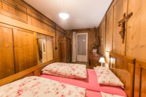 two beds in a room with wooden walls at Casa Sartori in Tesero