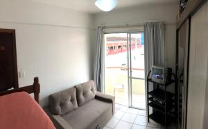 a living room with a couch and a sliding glass door at Lindo apartamento super completo em Meia Praia, 100 metros do mar e 10 quadras do centro in Itapema