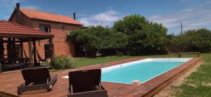 a swimming pool with two chairs and a house at Casa Amigable y Disfrutable in La Coronilla