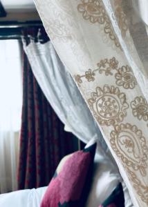 een wit gordijn met paarse kussens op een bed bij House of Agnes in Canterbury