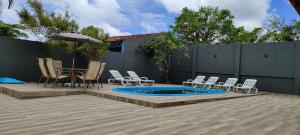 um pátio com cadeiras e uma piscina com um guarda-sol em Lindo Sobrado c/ Piscina e conforto próximo do mar em Itapoá