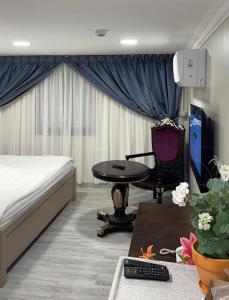a bedroom with a bed and a table and a chair at شقق المربعة للشقق المخدومة in Ruqaiqah