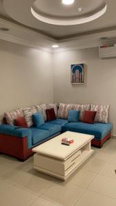 a living room with a blue couch and a coffee table at شقق المربعة للشقق المخدومة in Ruqaiqah