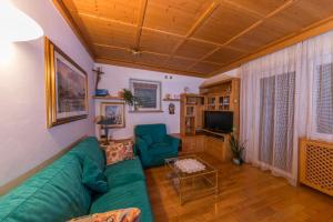 een woonkamer met een groene bank en een televisie bij Casa Trettel in Tesero
