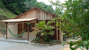 a small house with a hammock in front of it at Canto do Sabiá PETAR Hospedagem in Iporanga