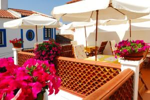 a balcony with flowers and a table and umbrella at Casa Do Adro Da Igreja Turismo De Habitação in Vila Nova de Milfontes