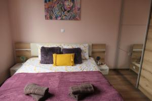 um quarto com uma cama grande com cobertor roxo e almofadas amarelas em Nikol 2 Deluxe em Velingrad