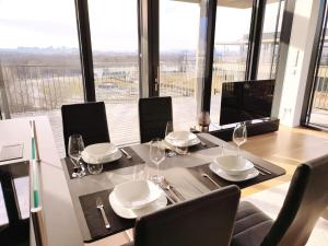 a dining room with a table and chairs and windows at Panorama Apartment Vienna - free parking, sauna & fitness in Vienna