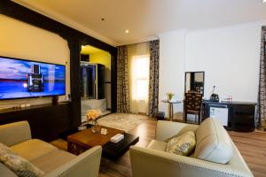 فندق ميلينيا العليا في الرياض: غرفة معيشة مع أريكة وتلفزيون