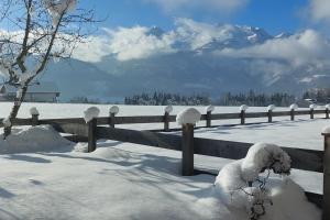 a fence covered in snow with mountains in the background at Urlaub mit Aussicht in Pfarrwerfen