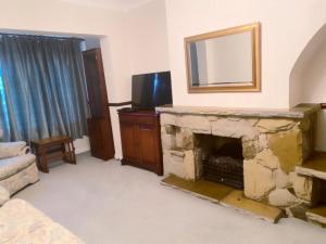 ein Wohnzimmer mit einem Steinkamin und einem TV in der Unterkunft Bexleyhealth Town Center 5 Bedroom Luxurious Home in Bexleyheath