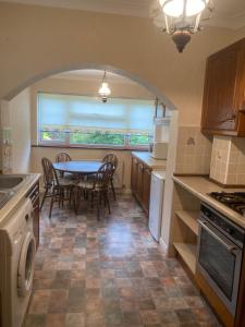 eine Küche mit einem Tisch und Stühlen in einer Küche in der Unterkunft Bexleyhealth Town Center 5 Bedroom Luxurious Home in Bexleyheath