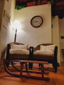 2 Stühle und ein Tisch mit einer Uhr an der Wand in der Unterkunft La Tana del Riccio in Abbadia San Salvatore
