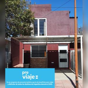 una casa rosa con un cartel azul delante de ella en Aqua Duplex en Villa Carlos Paz