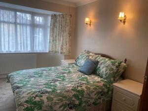 a bedroom with a bed with a flowered blanket and a window at Bexleyhealth Town Center 5 Bedroom Luxurious Home in Bexleyheath