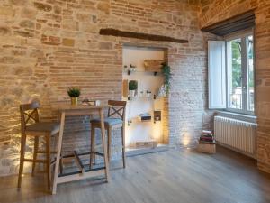 une salle à manger avec un mur en briques, une table et des chaises dans l'établissement Residenza Donna Iohanna, à Gubbio