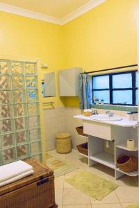 a yellow bathroom with a sink and a shower at The Zambarao Farm House in Naivasha