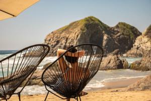a person sitting in a chair on a beach at Hotel Noga in Zipolite