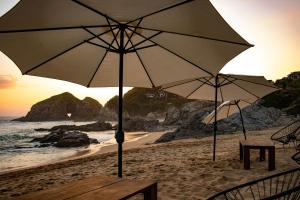 a couple of umbrellas on a beach with the ocean at Hotel Noga in Zipolite