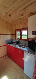 a kitchen with red cabinets and a sink in a cabin at La Claud'Roulotte - Gîte du Moulin 62130 Pierremont in Pierremont