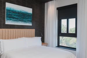 1 dormitorio con cama blanca y ventana en Century City Hotel Bridgewater, en Ciudad del Cabo