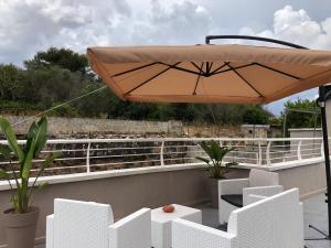 une terrasse avec des chaises blanches et un parasol dans l'établissement Apulia Tourist Salento, à Gemini