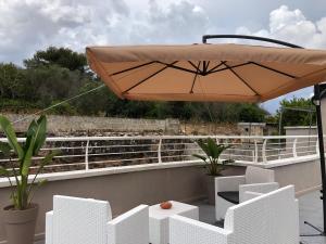 un patio con sillas blancas y una sombrilla en Apulia Tourist Salento, en Gemini