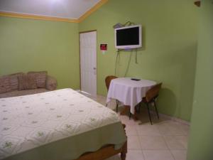 a bedroom with a bed and a table and a tv at Pavillon Des Receptions & Hotel in Port-au-Prince