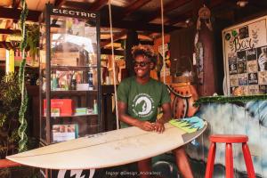 a man is holding a surfboard in a room at Guarda Encantada Surf Hostel in Guarda do Embaú