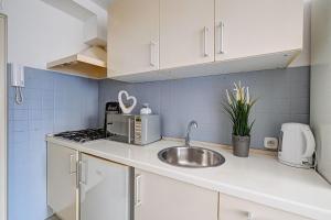 a kitchen with white cabinets and a sink at Noctis Apartment Bagno in Warsaw