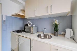 Una cocina con gabinetes blancos y un fregadero. en Noctis Apartment Bagno, en Varsovia