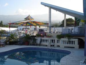 una piscina con patio y sombrilla en Pavillon Des Receptions & Hotel, en Puerto Príncipe