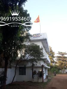 ein weißes Gebäude mit einer Flagge darüber in der Unterkunft Mahadev Guest House And Resort in Dhamtari